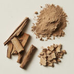 Three forms of cinnamon are displayed on a white surface: whole cinnamon sticks, crushed cinnamon pieces, and a pile of ground cinnamon powder. UK