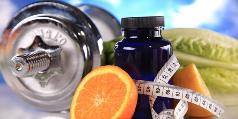 a dumbbell, a blue supplement bottle, an orange cut in half, lettuce, and a measuring tape are displayed against a blue sky background, representing health and fitness concepts. uk