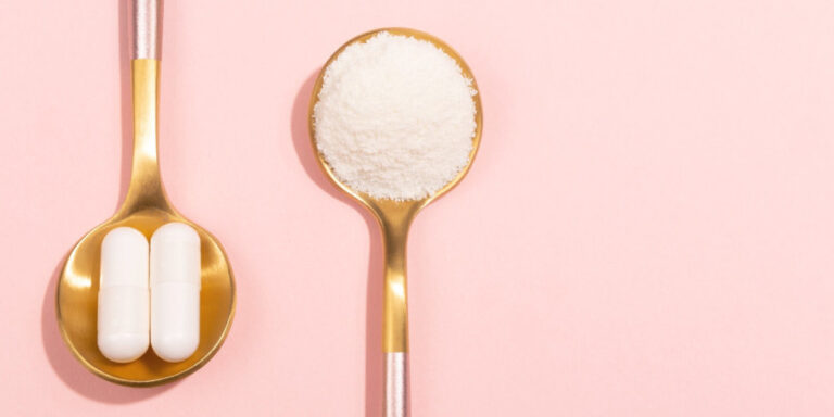 two gold spoons on a pink background: one holds two white capsules, the other holds a heap of white powder. uk