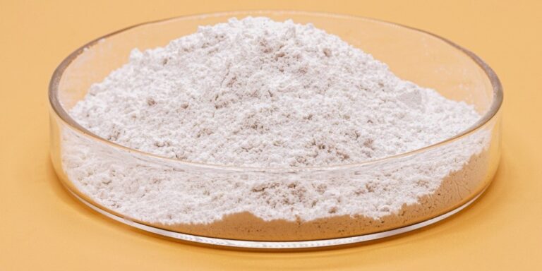 a clear, shallow dish filled with a mound of fine white powder sits on a solid light orange surface. uk