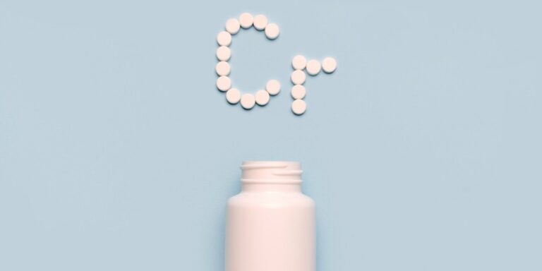 a white pill bottle with its cap off sits below white round tablets arranged to form the letters cr on a light blue background. uk